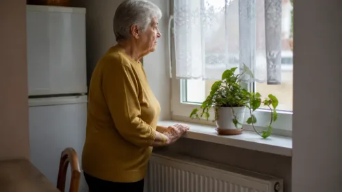 Senior sedí pri kuchynskom stole a pozerá na výpis z dôchodku, vedľa neho stojí hrnček s čajom
