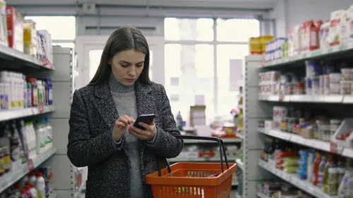 Žena so smartfónom a kalendárom na kuchynskom stole počas ranného svetla