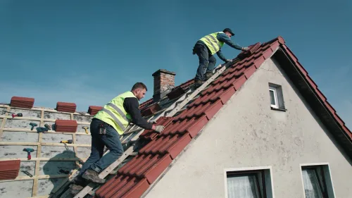 Remeselníci kladú novú strešnú krytinu na rodinný dom počas slnečného dňa