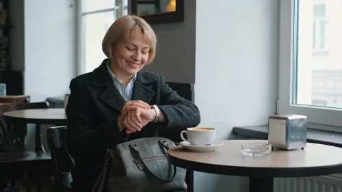Žena stredného veku pozerá do kalendára a kalkuluje pri stole s dokumentmi