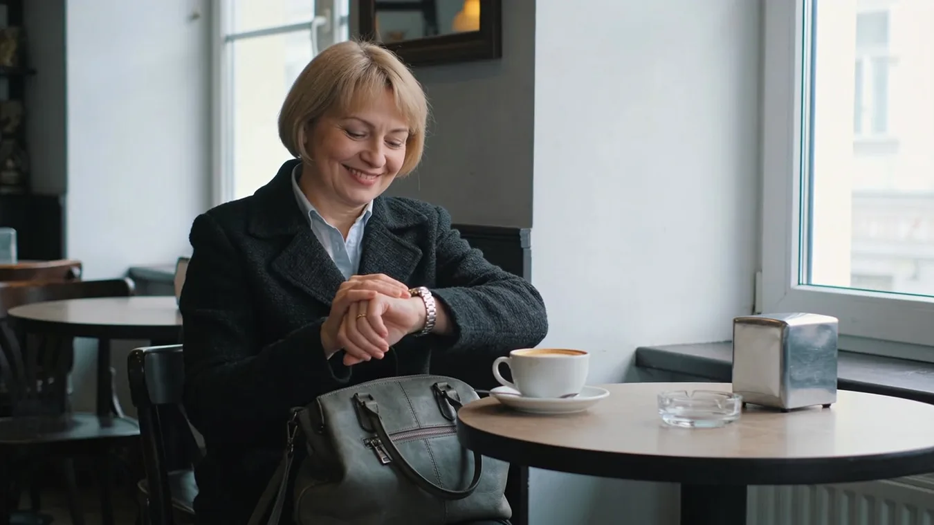 Žena stredného veku pozerá do kalendára a kalkuluje pri stole s dokumentmi